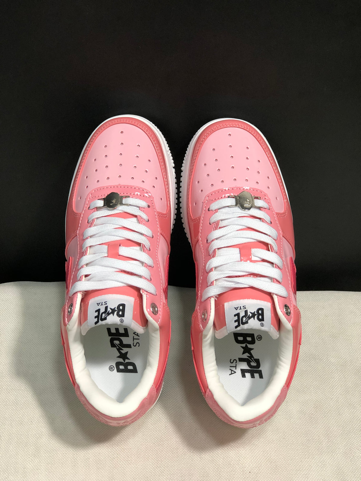 Top-down view showing the pink perforated toe boxes, white laces, and BAPE Sta insoles.