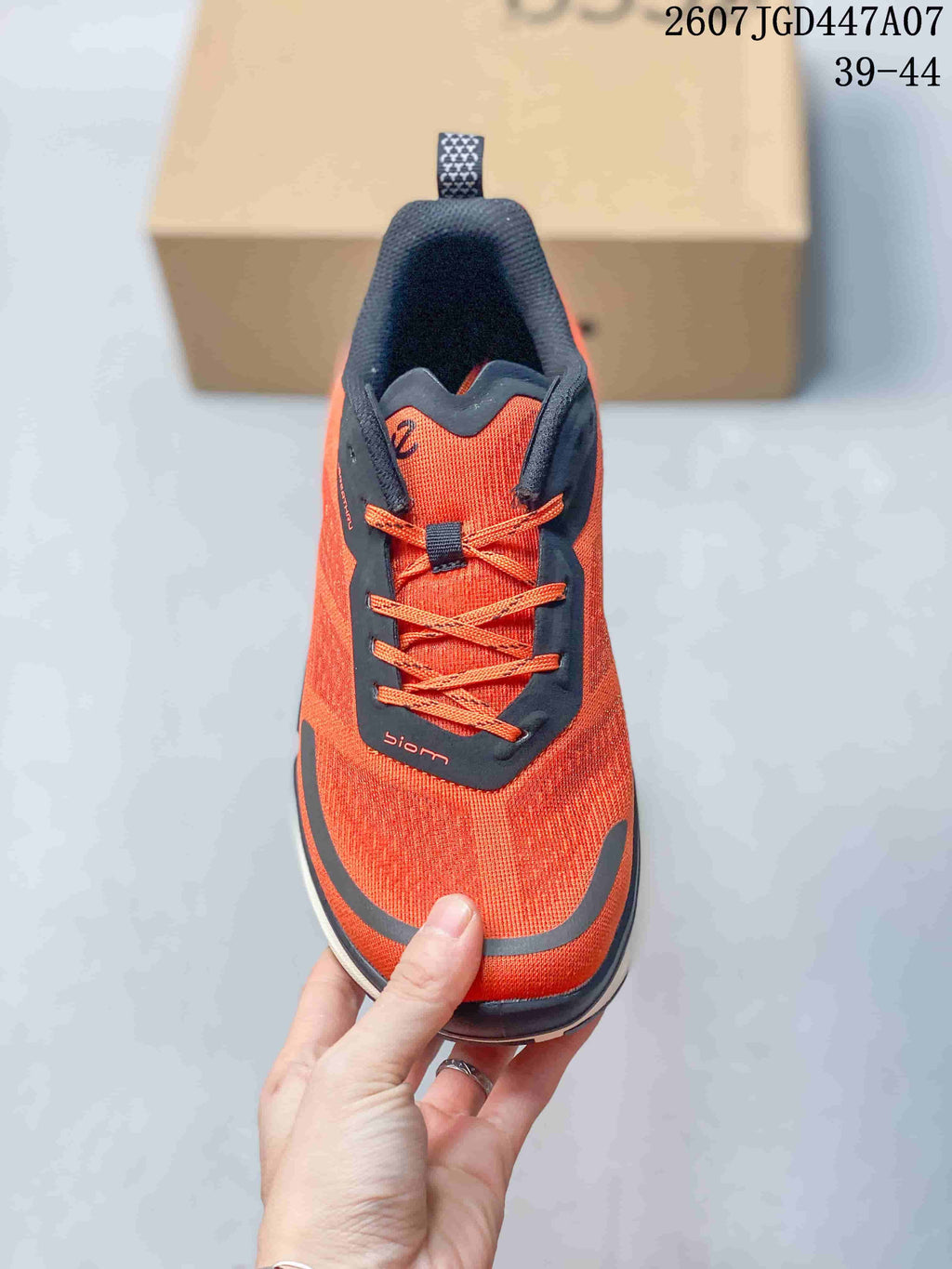 Top view of an orange ECCO sneaker showing the dark tongue and eyestay, orange laces, and BIOM marking.