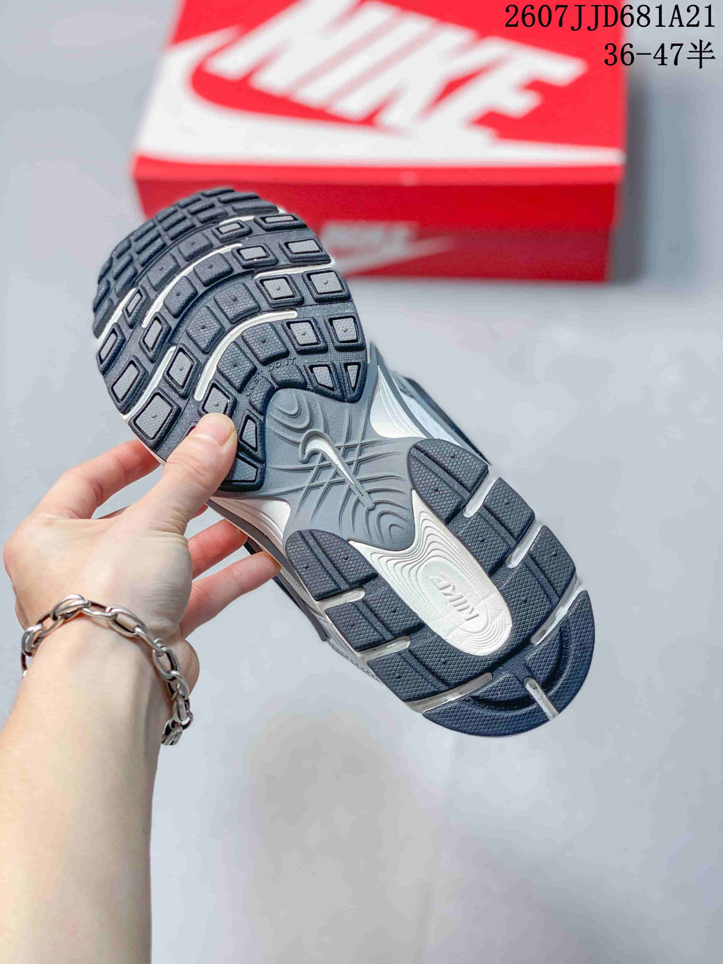 Underside view of a Nike V5 RNR sneaker showing the dark patterned rubber outsole and sculpted midsole.