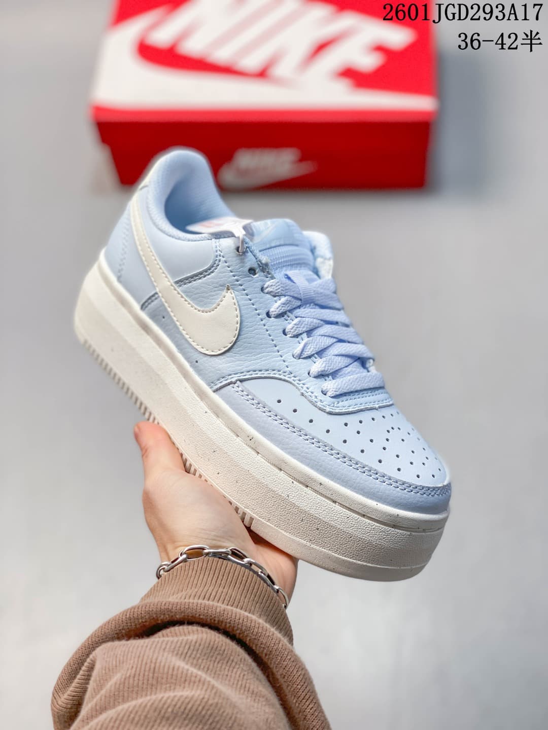 Angled side view of the light blue and white sneaker showing the Swoosh, perforated toe and thick sole.