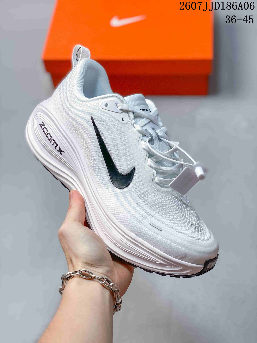 Angled side view of a white Nike Vomero running shoe showing the black Swoosh, woven-looking upper and sculpted midsole.