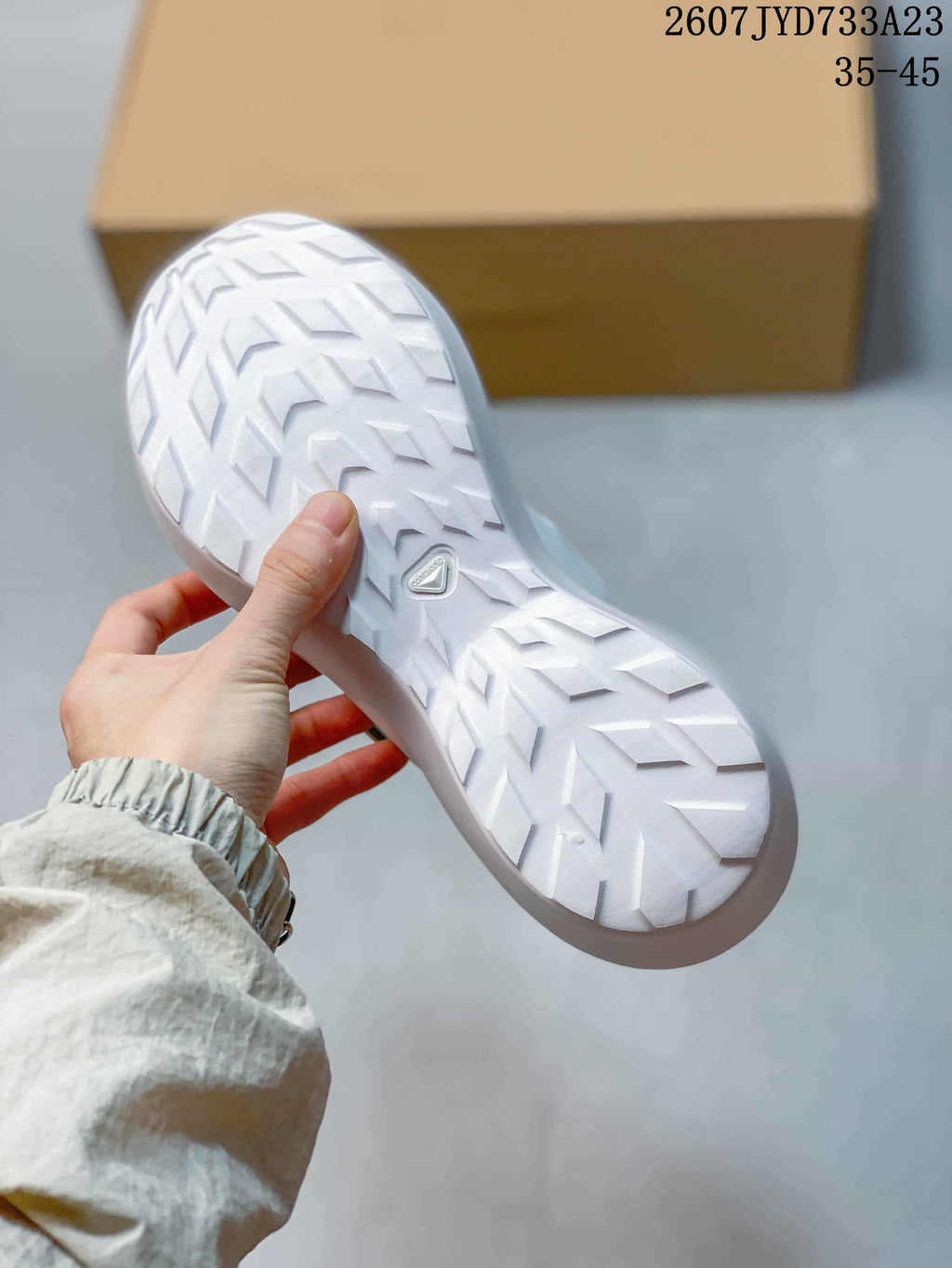White sneaker outsole showing a repeating directional tread pattern and a small central emblem.