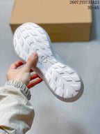 White sneaker outsole showing a repeating directional tread pattern and a small central emblem.