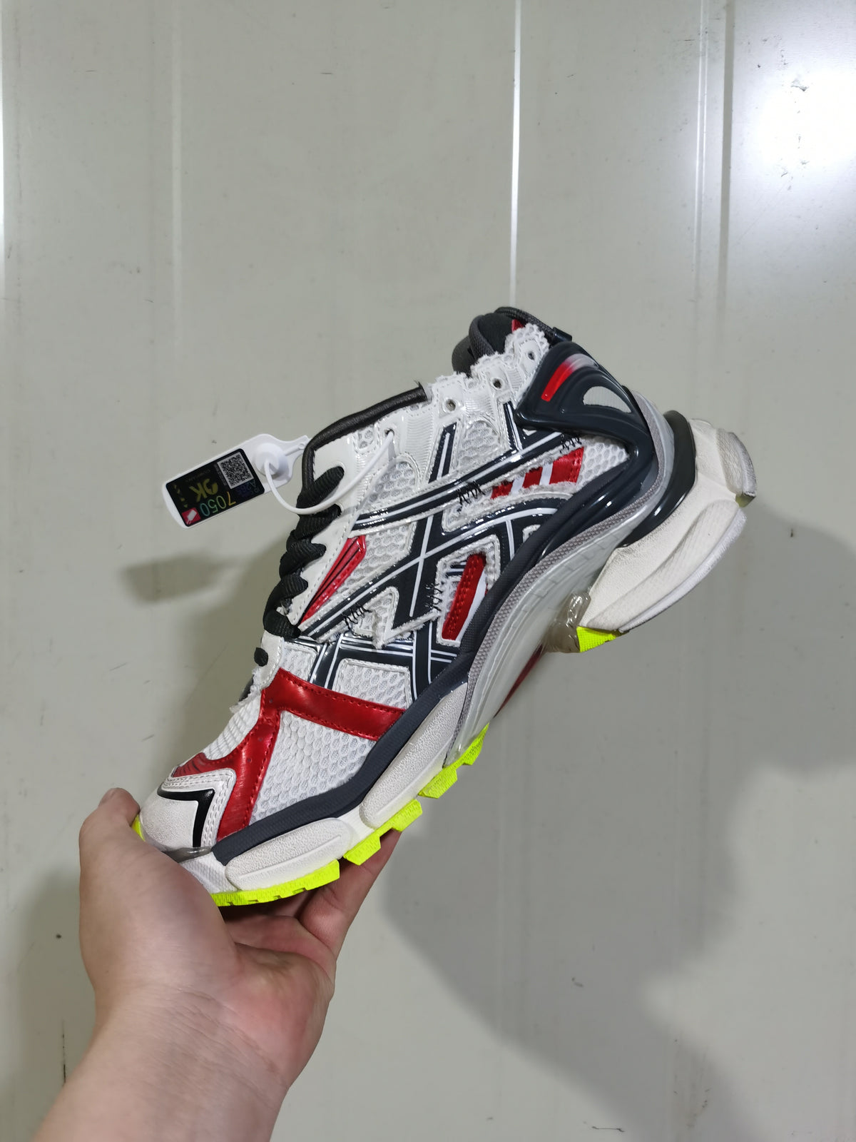 Side view of a Balenciaga Runner sneaker showing black, white and red layered panels with fluorescent yellow outsole accents.