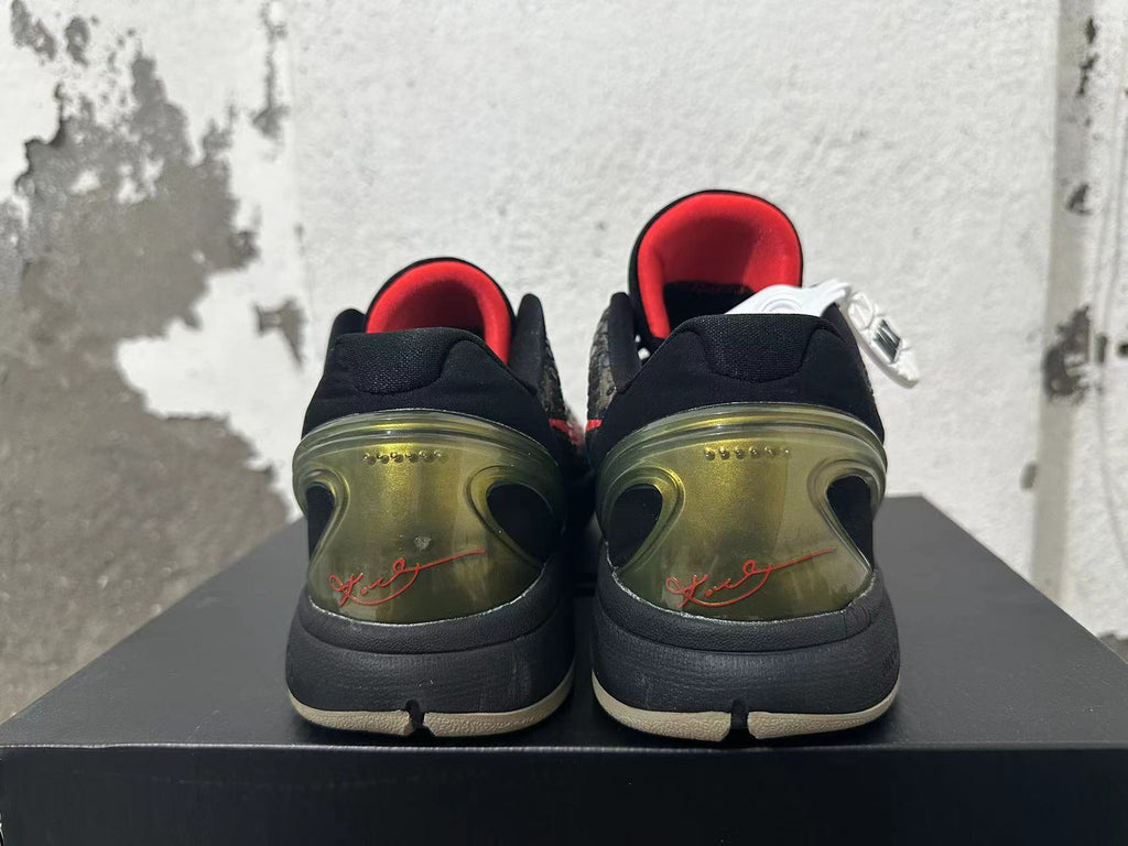 Rear view of black camouflage Nike Kobe shoes with red lining and translucent olive-toned heel panels.