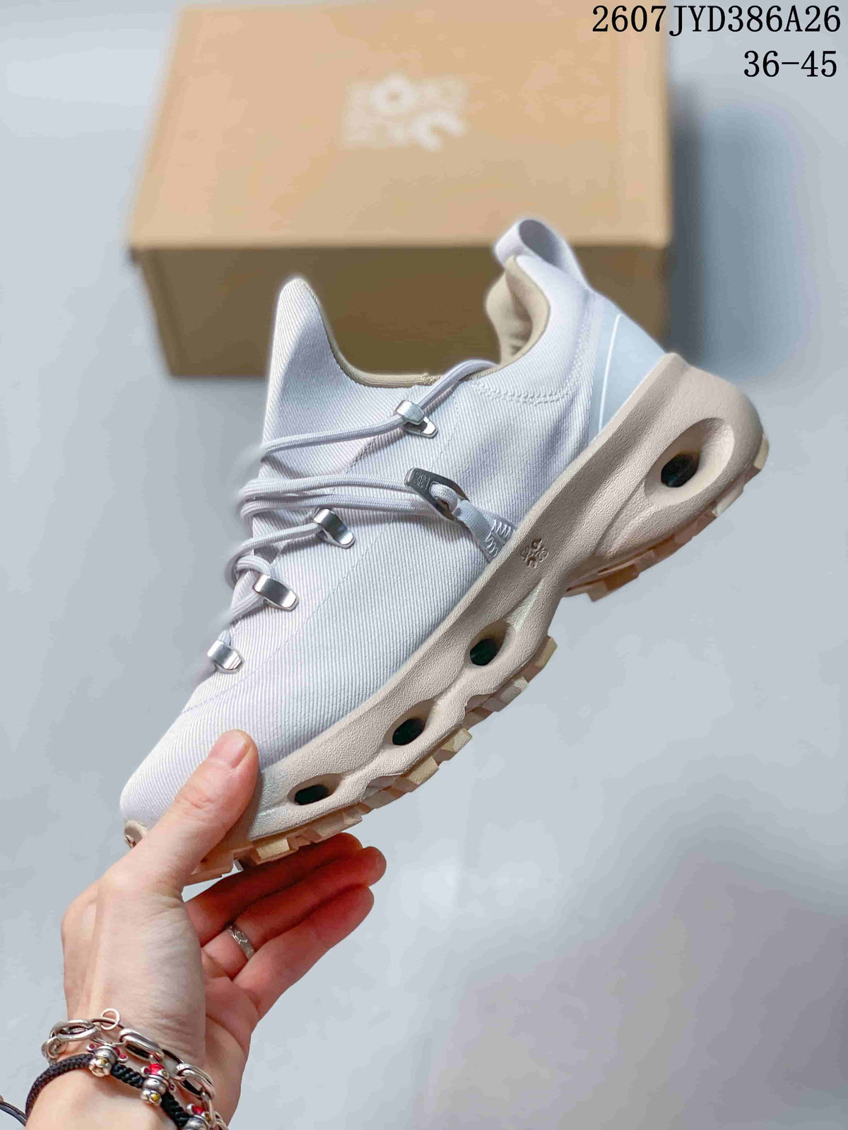 Side view of the light gray sneaker showing layered cord lacing, a sculpted midsole with openings, and a lugged outsole.