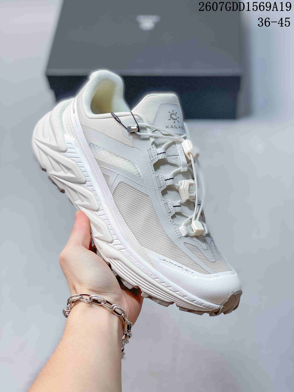 Angled side view of the white KAILAS sneaker showing the upper panels, lace hardware and textured outsole.