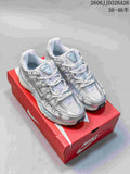 Pair of silver and white Nike P-6000 sneakers with pale blue accents on a red shoebox