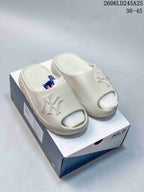 Pair of light-colored open-toe slide sandals with raised NY lettering.