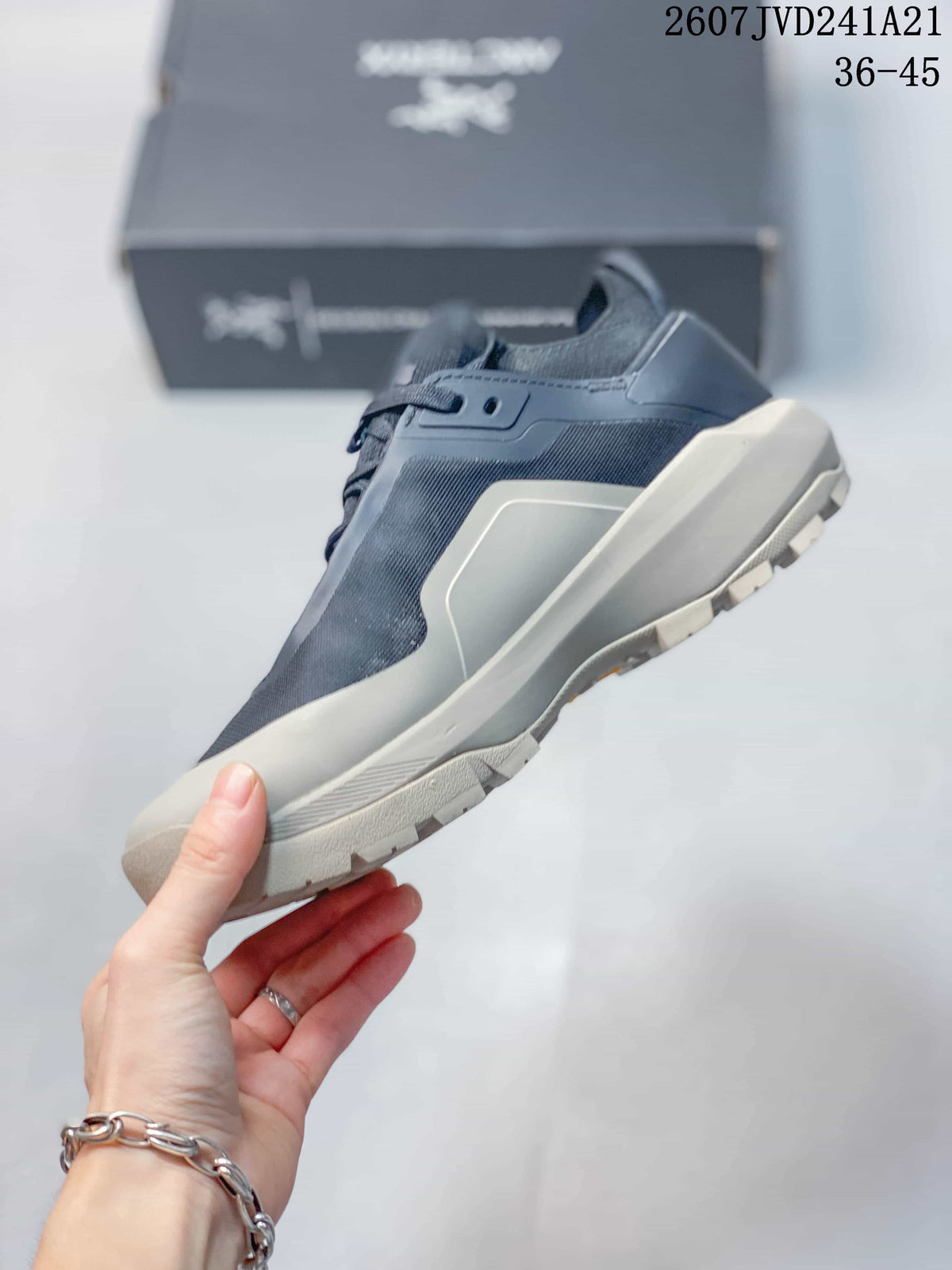 Side profile showing the navy and gray upper, layered midsole, lace closure, and lugged outsole.