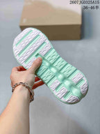 Underside view of a mint green and white sneaker showing the sculpted outsole and traction sections.