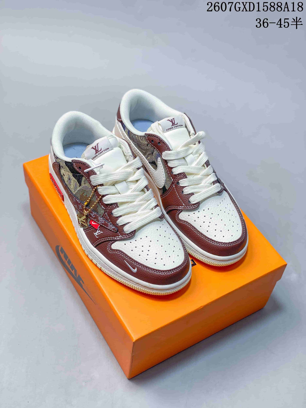 Pair of brown, white, and patterned low-top sneakers displayed on an orange shoebox, with white laces and contrasting overlays.