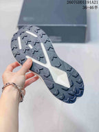 Underside view of the sneaker showing the dark lugged outsole with a central white support section.