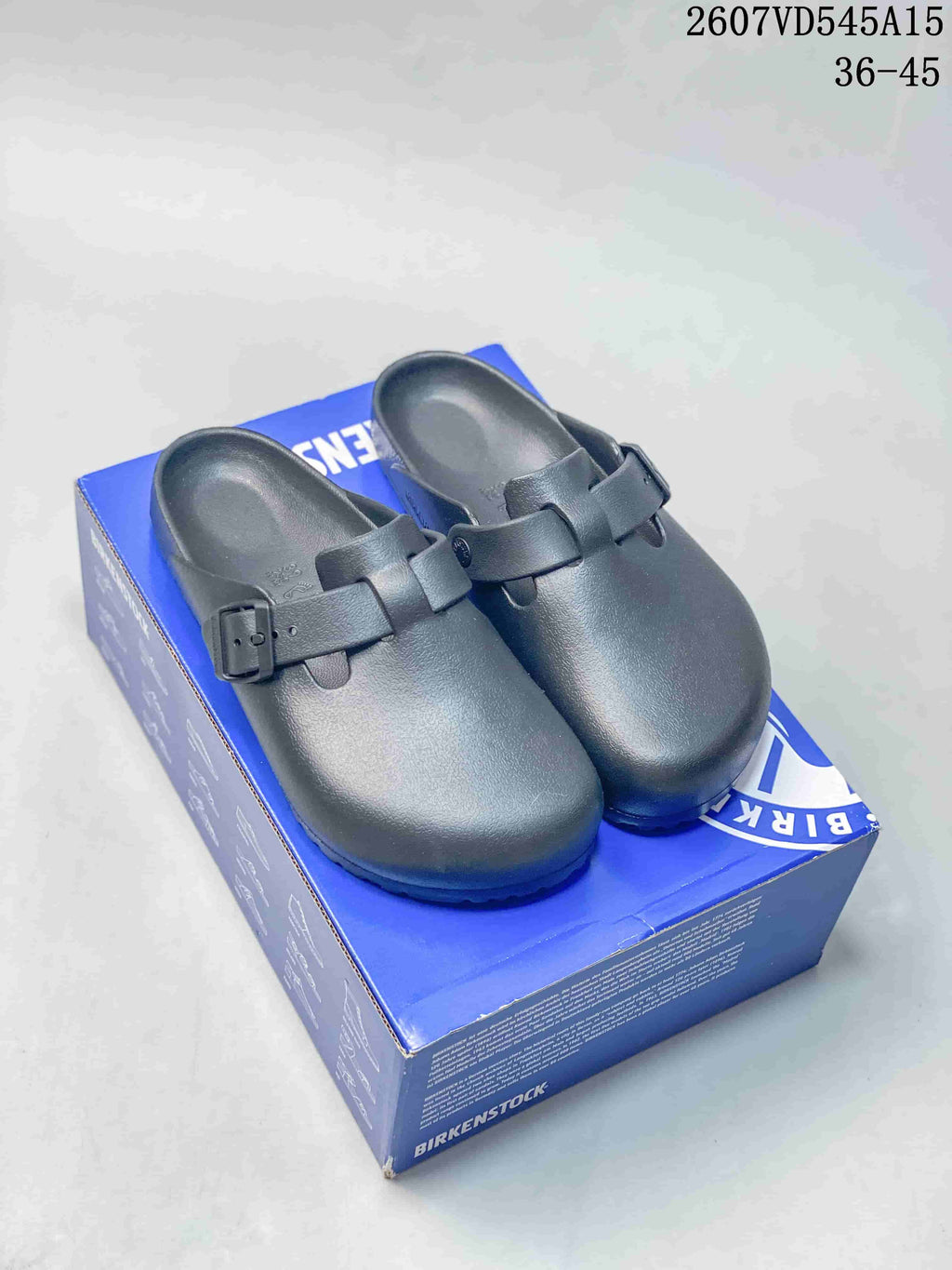 Pair of black closed-toe buckle sandals displayed on a blue shoe box, with the product code and EU 36–45 range overlaid.