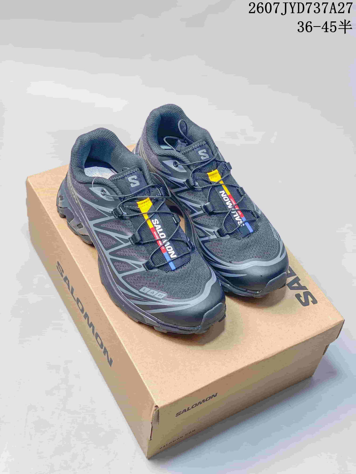 Pair of dark gray and black Salomon XT-6 GTX sneakers displayed on a Salomon shoebox.