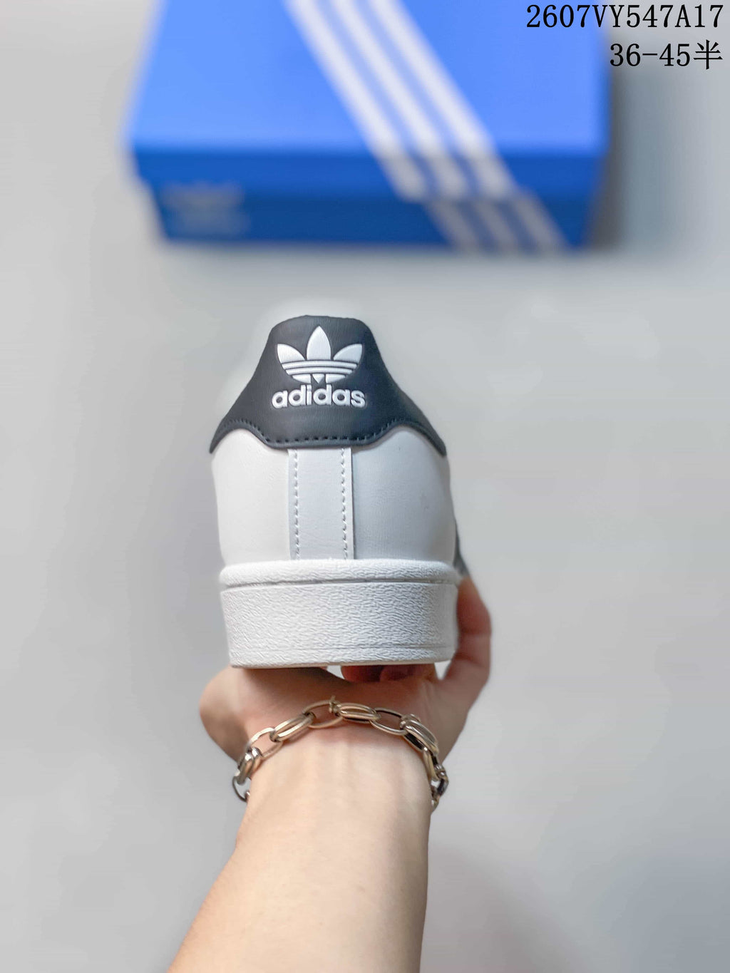 Rear view of a white sneaker with a black heel tab and adidas Originals trefoil branding.