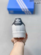 Rear view of a white sneaker with a black heel tab and adidas Originals trefoil branding.