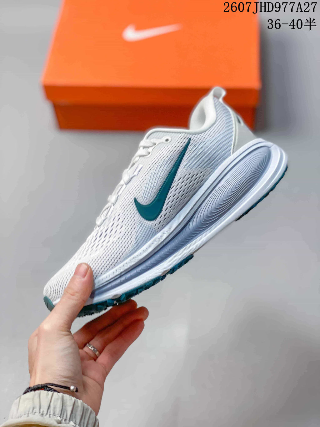 Side profile of the white sneaker showing the teal Swoosh, mesh-textured upper, layered midsole and teal outsole accents; overlay text shows style code 2607JHD977A27 and sizes 36–40.5.