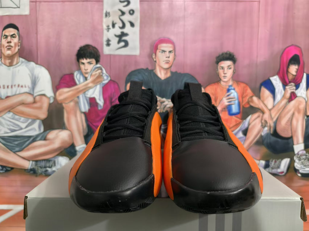 Front view of black and orange basketball sneakers with laces and rounded toe panels