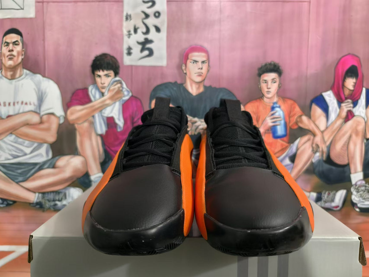 Front view of black and orange basketball sneakers with laces and rounded toe panels
