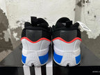 Rear view of white, blue, and black Adidas basketball shoes with red-orange collar trim