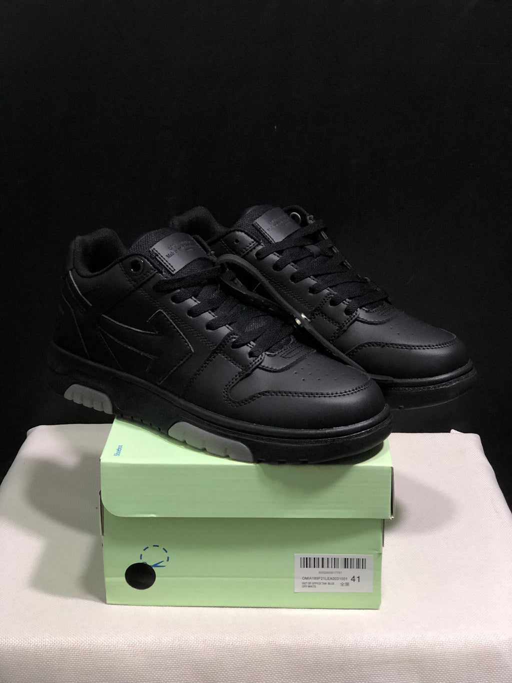 Pair of black low-top sneakers displayed on a light green shoe box; the box label shows size 41.