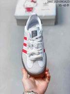 Top view of the sneaker showing white laces, a dark Hello Kitty tongue label, and red side stripes.