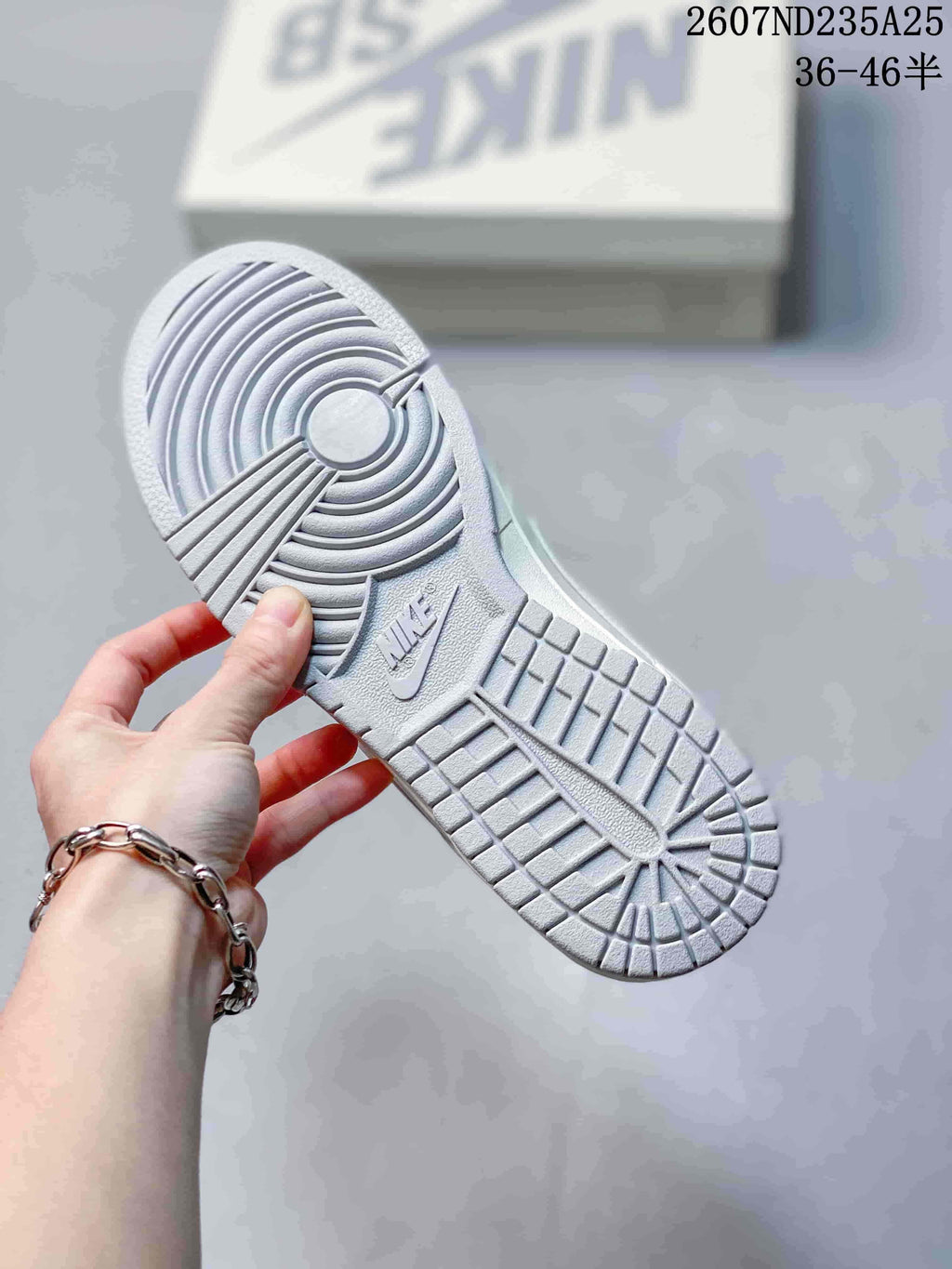Underside view of a white sneaker showing the textured rubber outsole and circular traction pattern.
