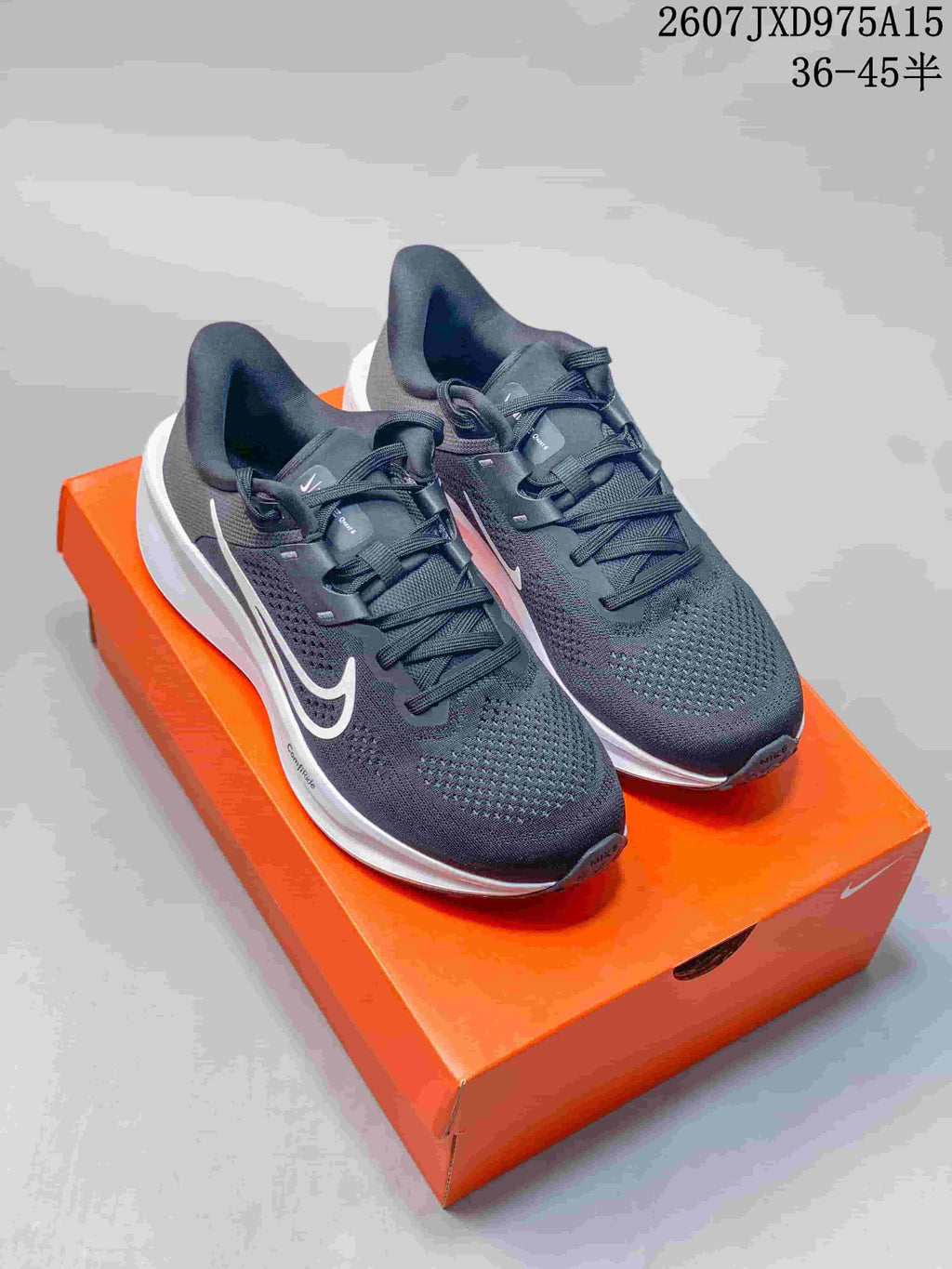 Pair of dark gray and white Nike Quest 6 running shoes displayed on an orange shoebox.