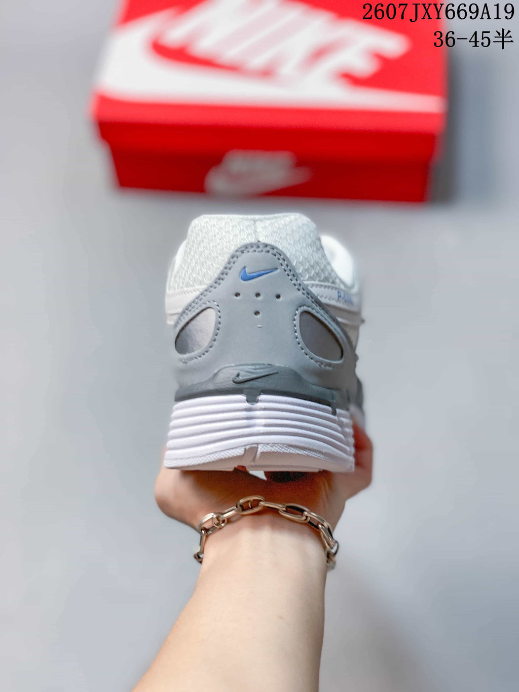 Rear view of a white and grey sneaker showing the padded heel, layered outsole, and small Nike branding.