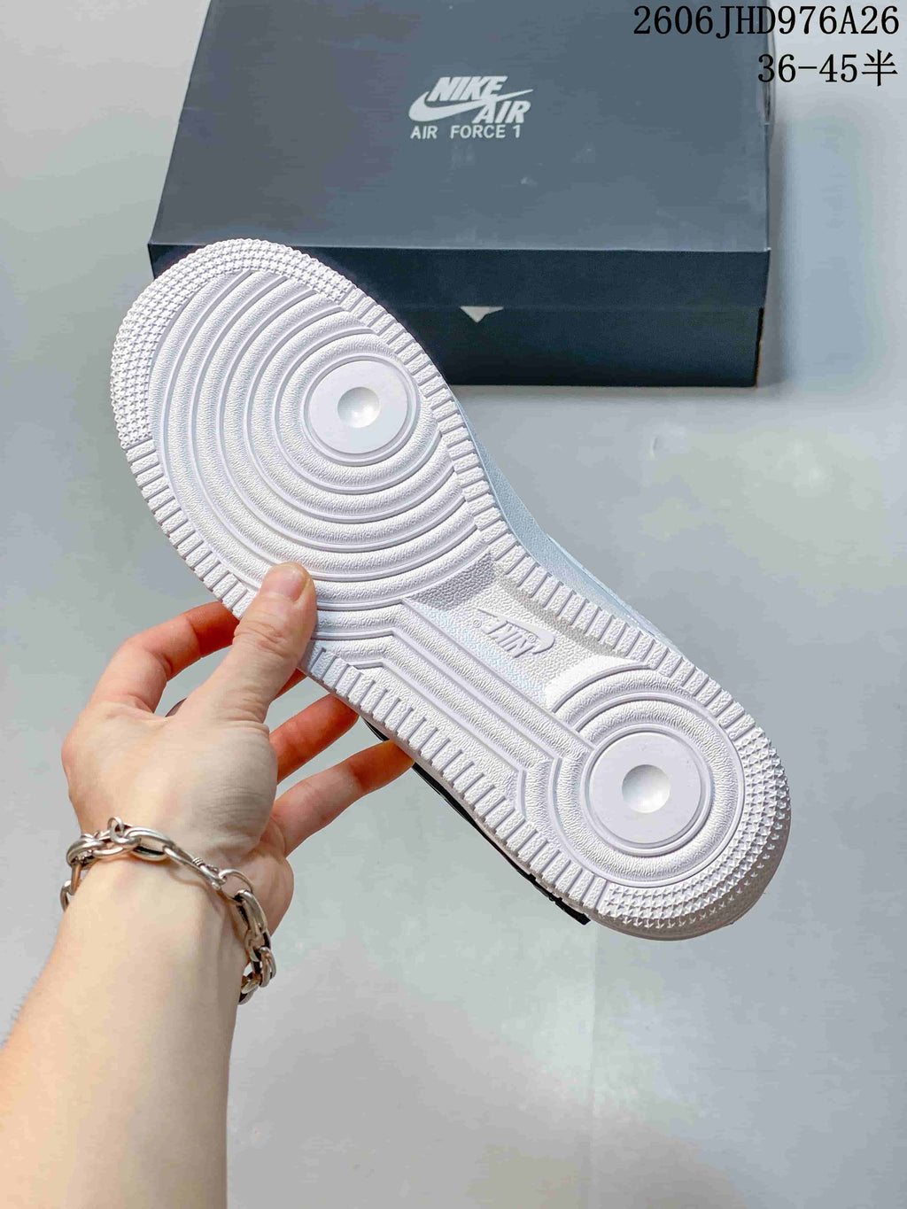 Underside of a white sneaker showing a textured outsole and circular traction patterns.