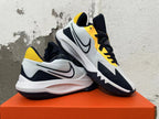 Pair of white, navy and yellow Nike basketball shoes shown from the side