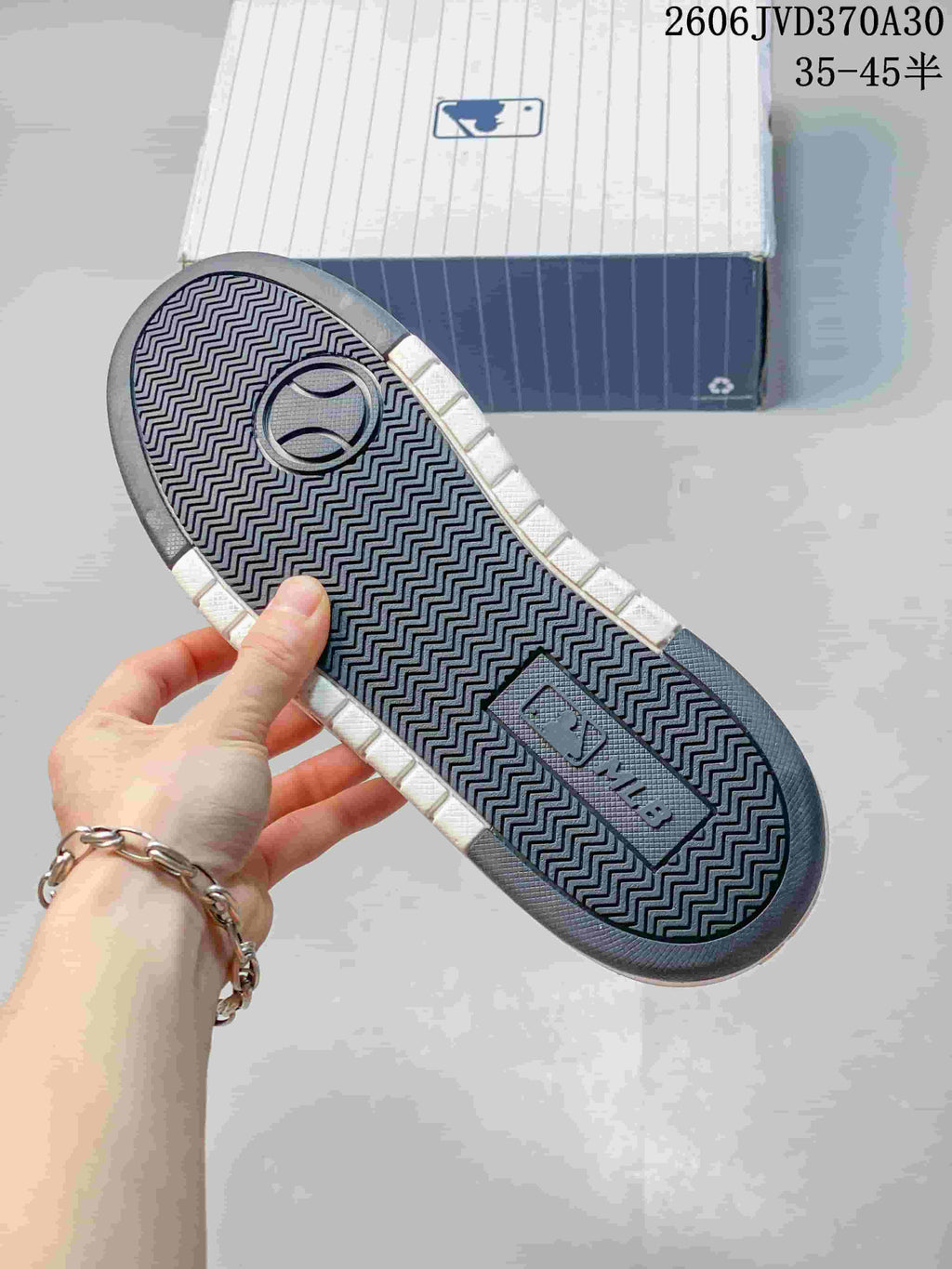 Underside of the sneaker showing a patterned dark outsole and white sidewalls.