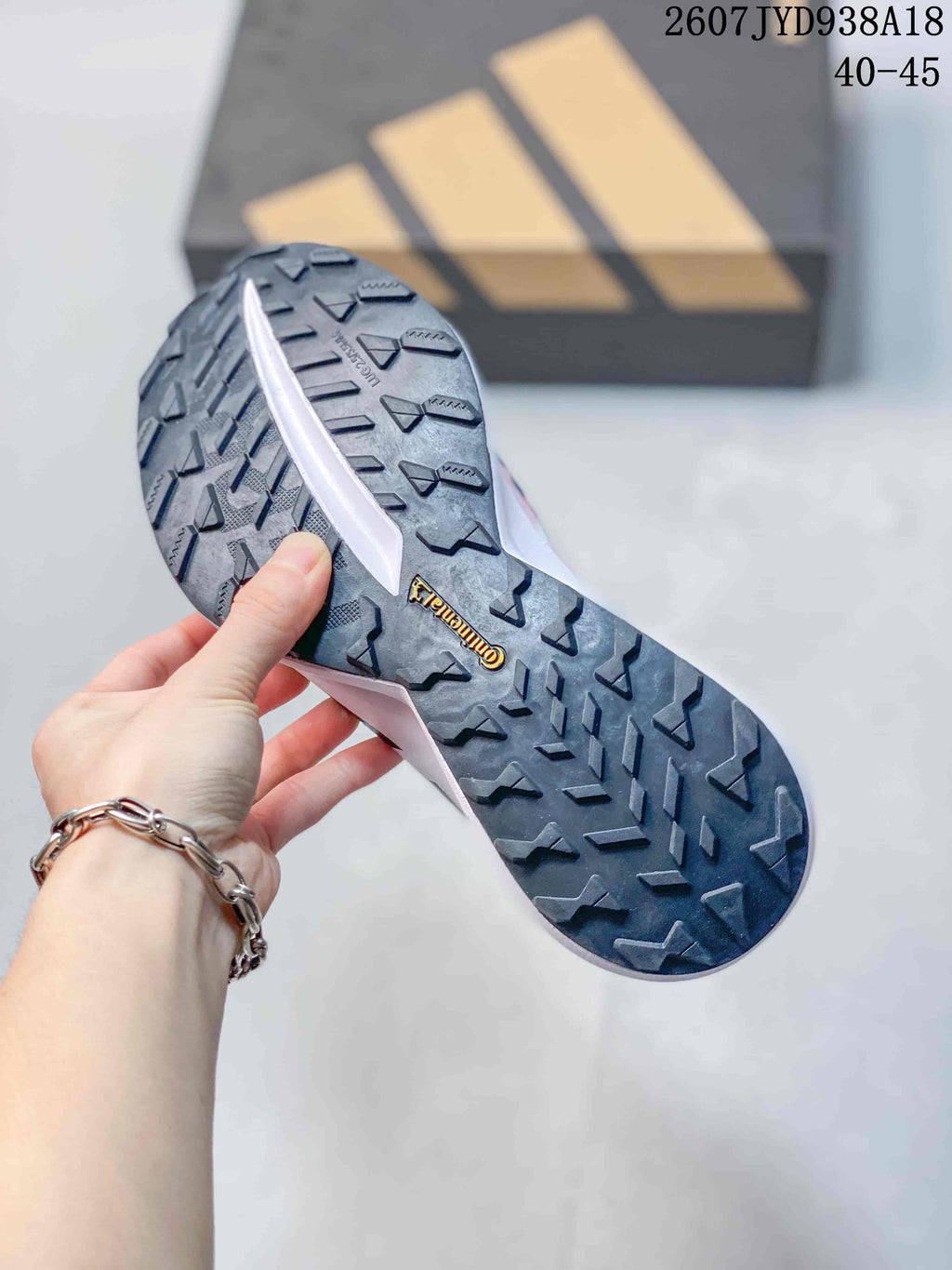 Close view of the black patterned outsole showing directional tread blocks and a central branded marking; size range text 40–45 is visible.