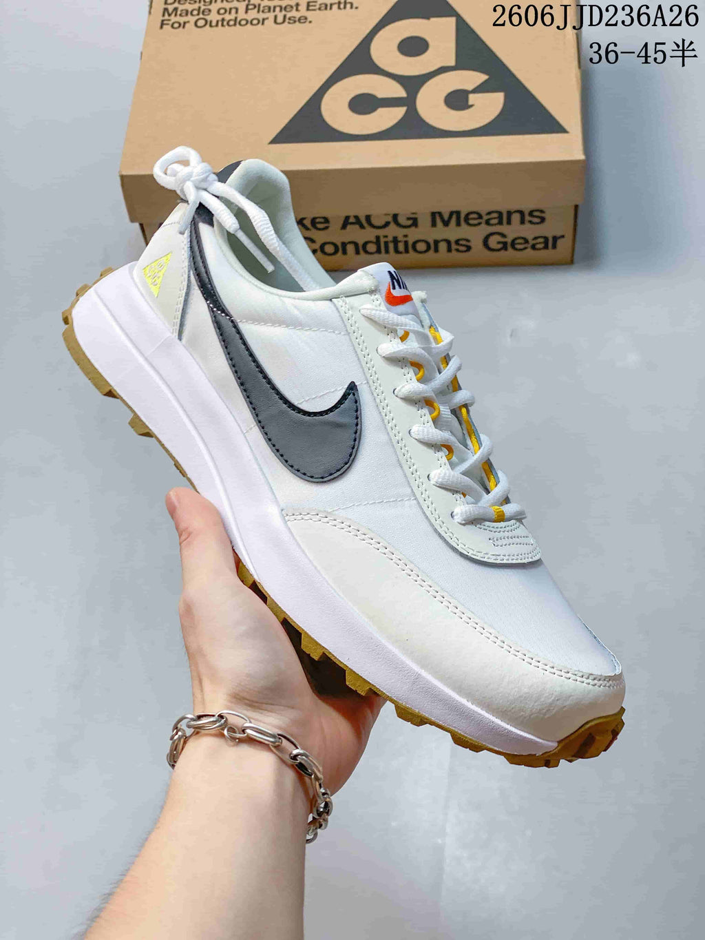 Angled side view of a white Nike ACG sneaker with dark side detailing, yellow accents, padded collar, and gum outsole.