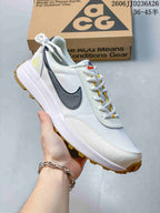 Angled side view of a white Nike ACG sneaker with dark side detailing, yellow accents, padded collar, and gum outsole.