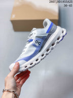 Side view of the white and blue trail sneaker showing the layered upper, On branding, cushioned midsole, and lugged outsole.