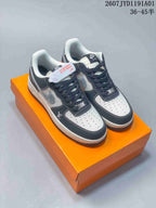 Pair of white, gray, and dark low-top sneakers displayed on an orange box