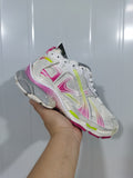 Close-up angled view of white Balenciaga Runner sneakers with pink, neon green, and gray layered accents.