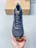 Front view of the navy high-top sneaker showing the lace system, toggle, tongue branding, and olive toe accent.