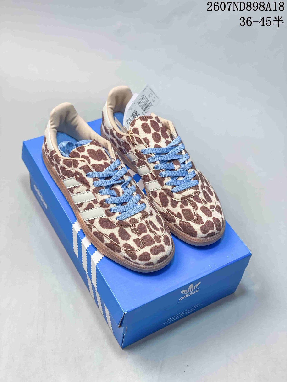 Brown-and-cream animal-print Adidas Samba OG sneakers with blue laces, white stripes and gum-colored soles.