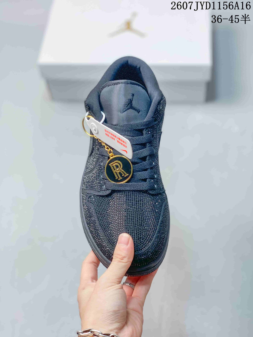 Front view of a black Jordan sneaker showing the embellished toe box, laces, tongue branding and decorative hangtags.