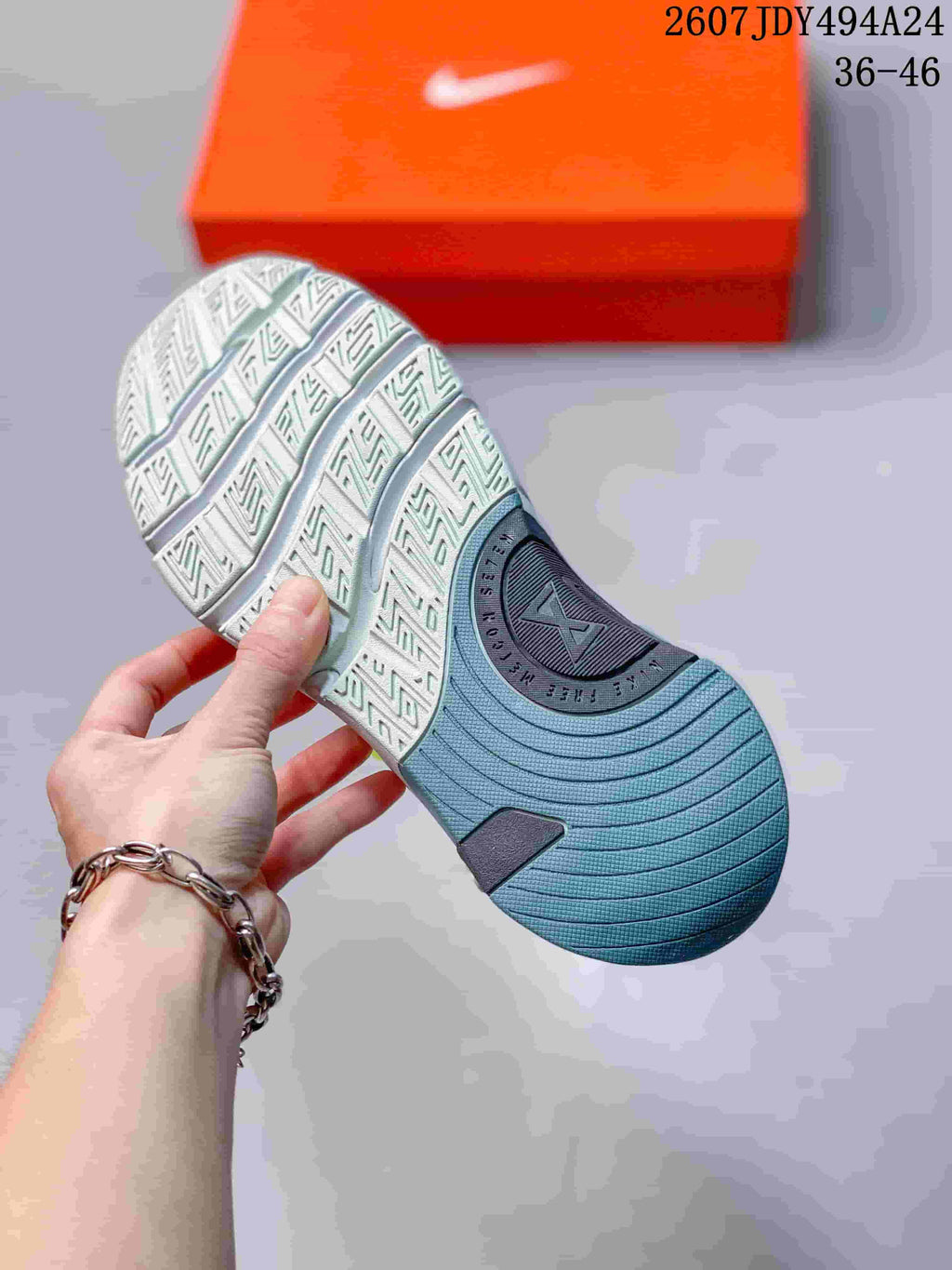 Underside view showing the patterned outsole of the light gray and blue training sneaker.