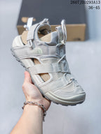 Angled close view of the light gray sandal showing The North Face branding, layered straps, open side panels, and treaded outsole.