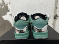 Rear view of green Nike Kobe basketball shoes with black collars and reflective-looking heel details.