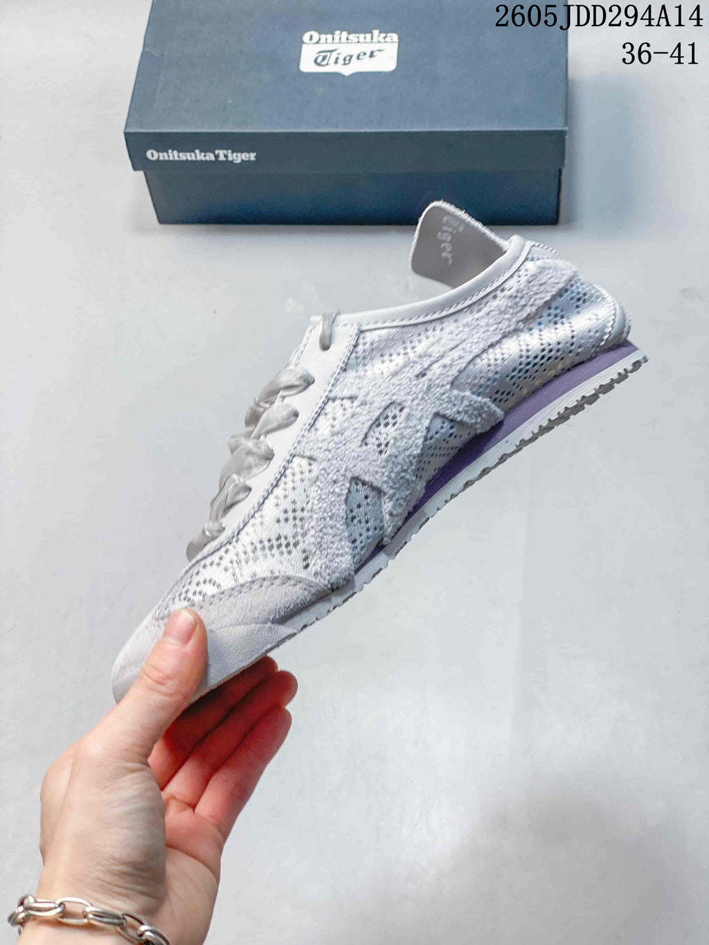 Side profile of the light gray textile sneaker showing the layered panels, lace-up front, low-top shape, and contrasting outsole.