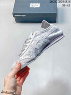 Side profile of the light gray textile sneaker showing the layered panels, lace-up front, low-top shape, and contrasting outsole.