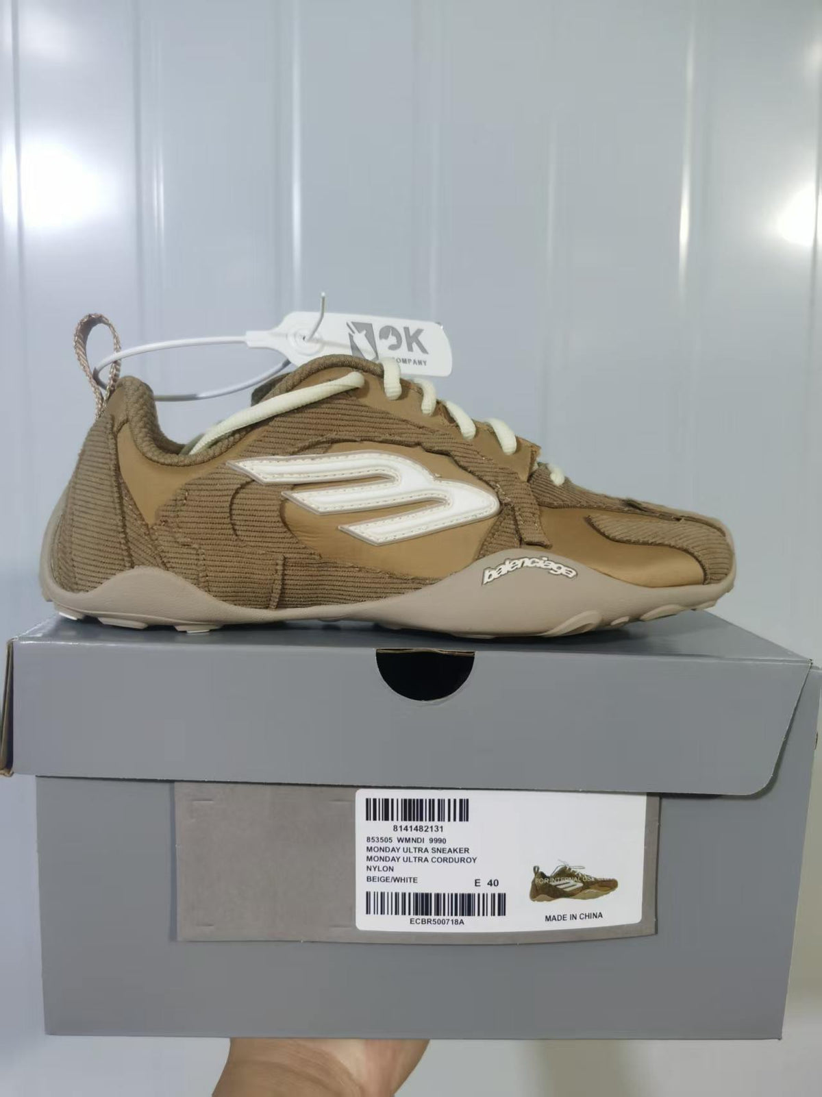 Side view of beige and white Balenciaga Monday Ultra sneakers displayed on the labeled shoebox.