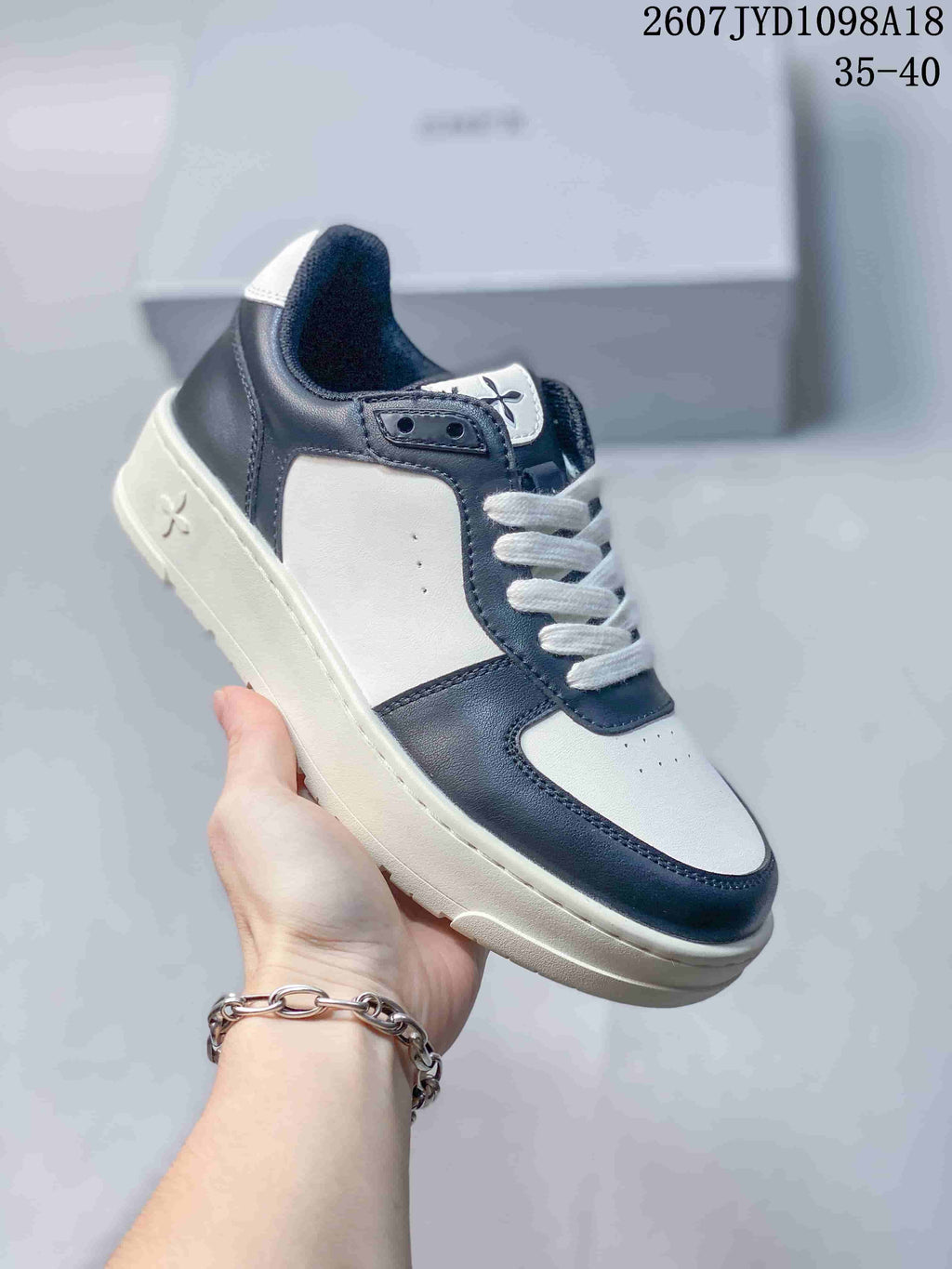 Close side view of a white and navy SMFK sneaker showing the layered sole, stitched panels, white laces, and side emblem.