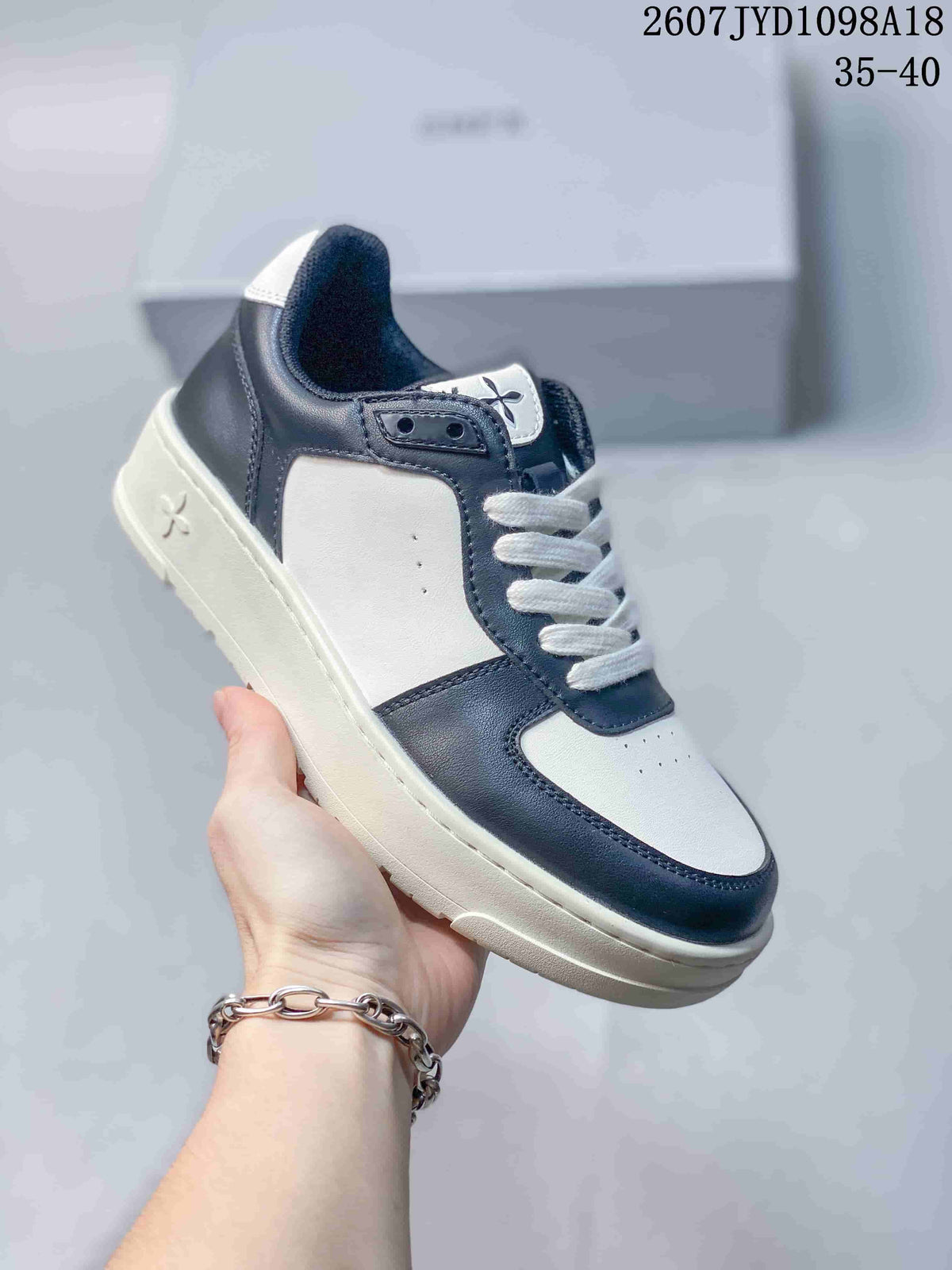 Close side view of a white and navy SMFK sneaker showing the layered sole, stitched panels, white laces, and side emblem.
